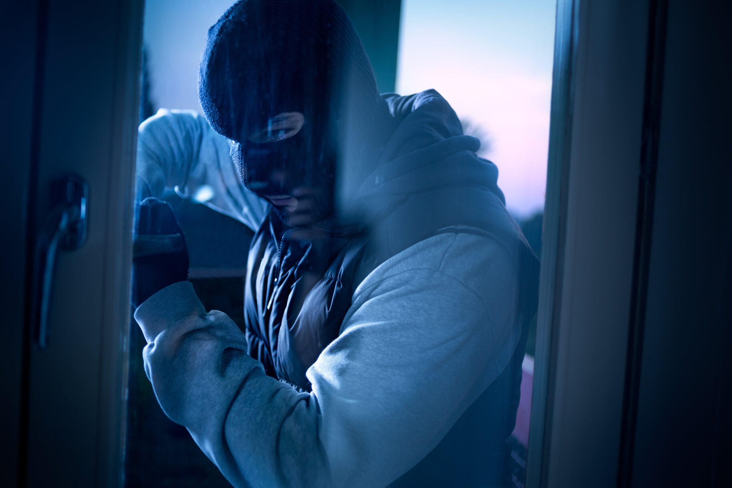 Burglar breaking into house through door - they need burglar alarms Colchester by Lenz Security
