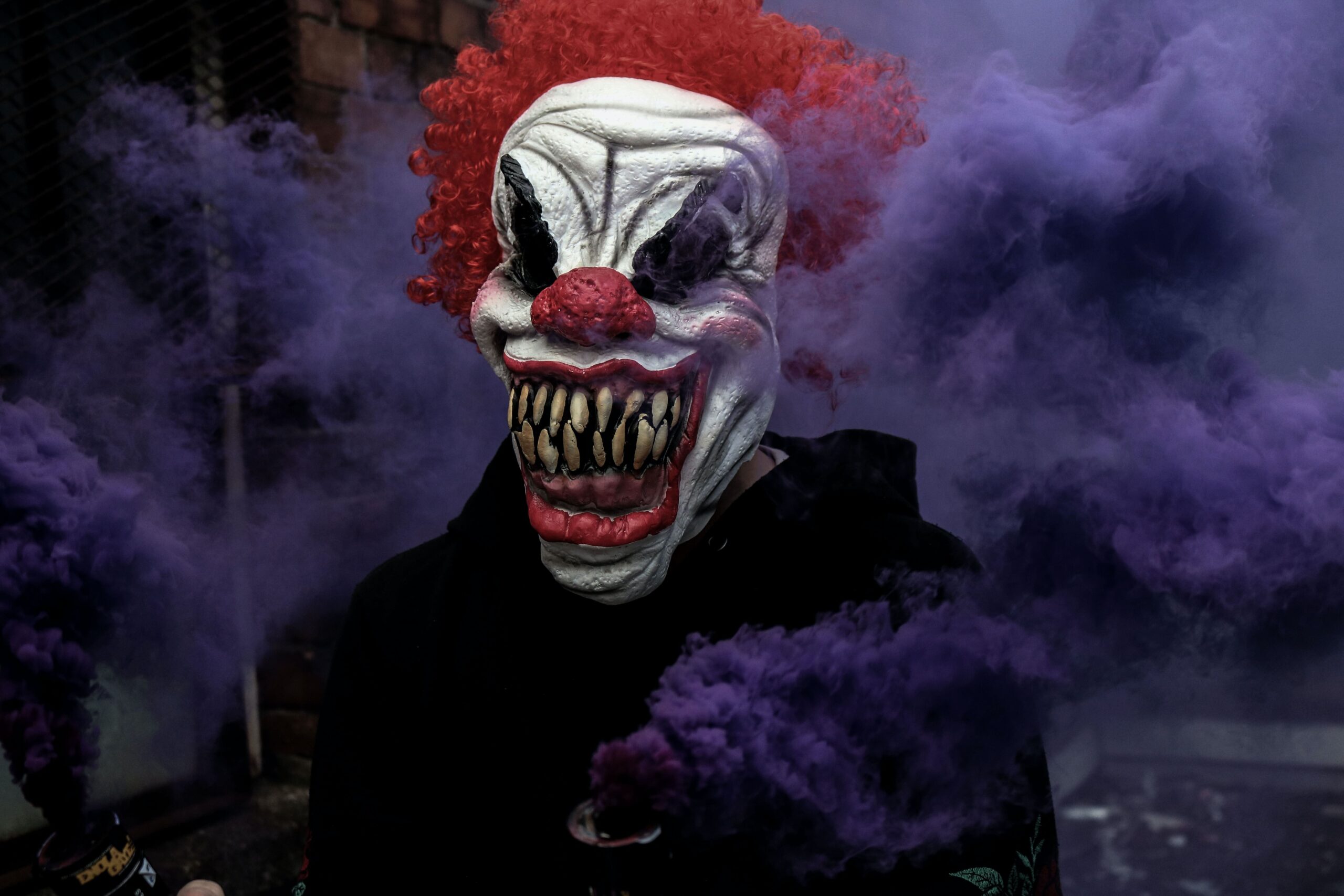 Scary clown mask with purple smoke in the background - home owners should get the best CCTV system solutions Colchester can offer to protect against those who take advantage of Halloween night
