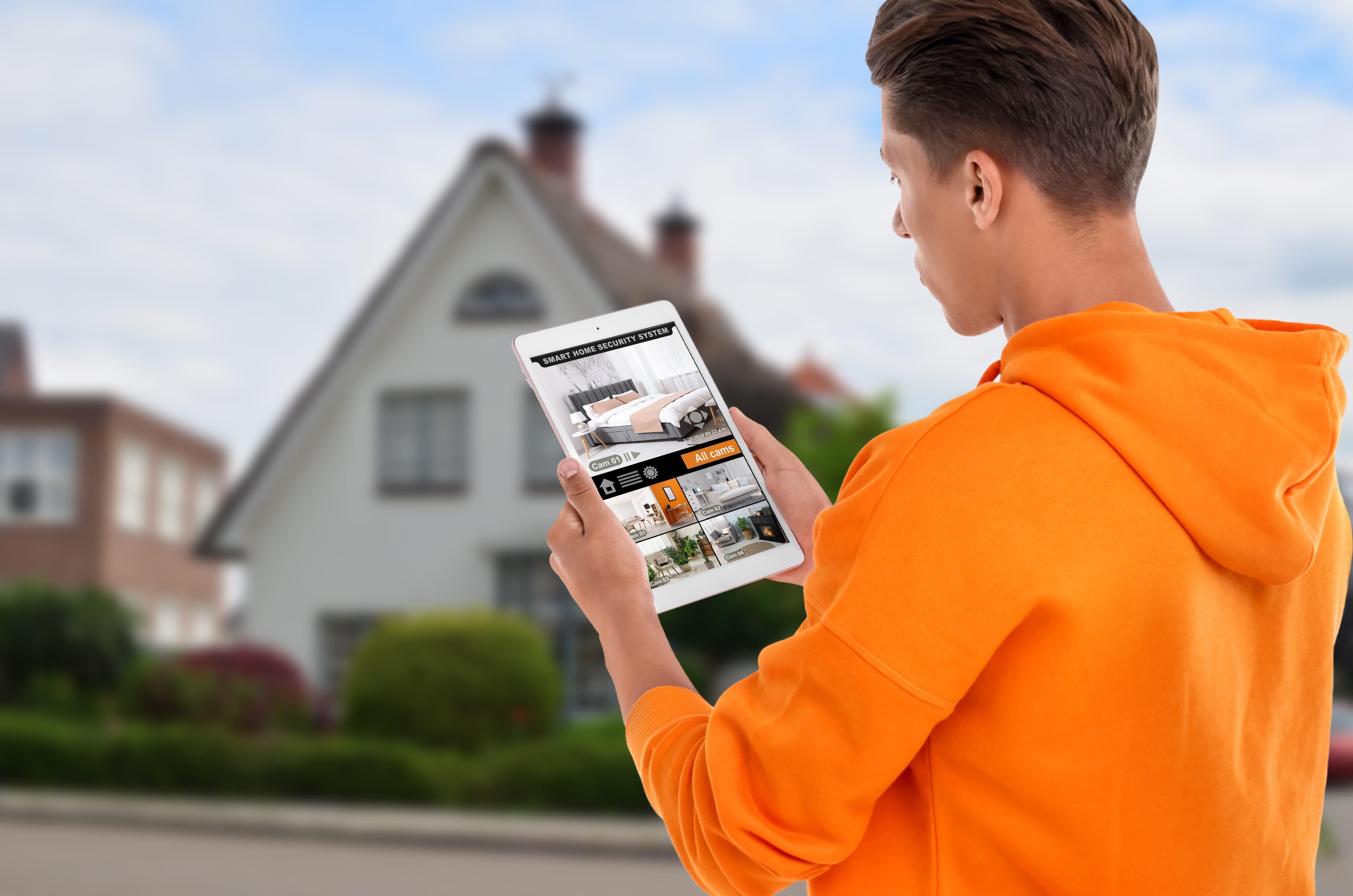 Remote Access CCTV Man outside home looks at remote access CCTV images on his smartphone